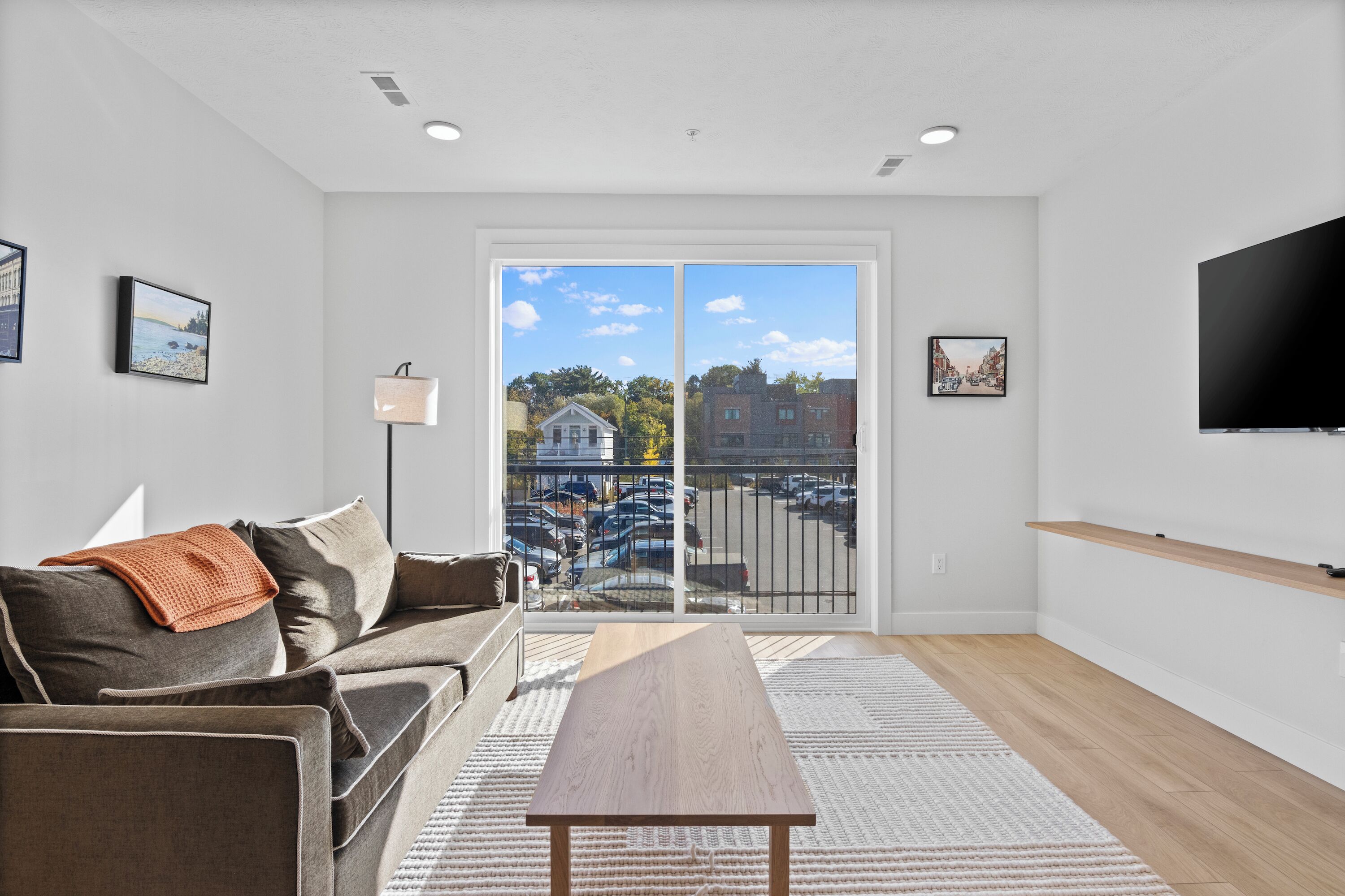 A modern living room with a sofa, a coffee table, and a TV mounted on the wall.