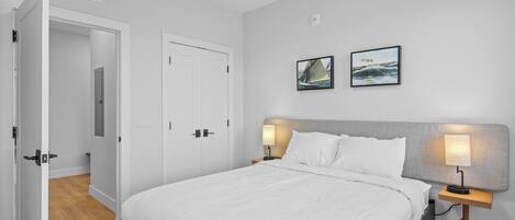 Une chambre à coucher avec un lit, deux lampes de chevet, une table de chevet et deux tableaux encadrés accrochés au mur.