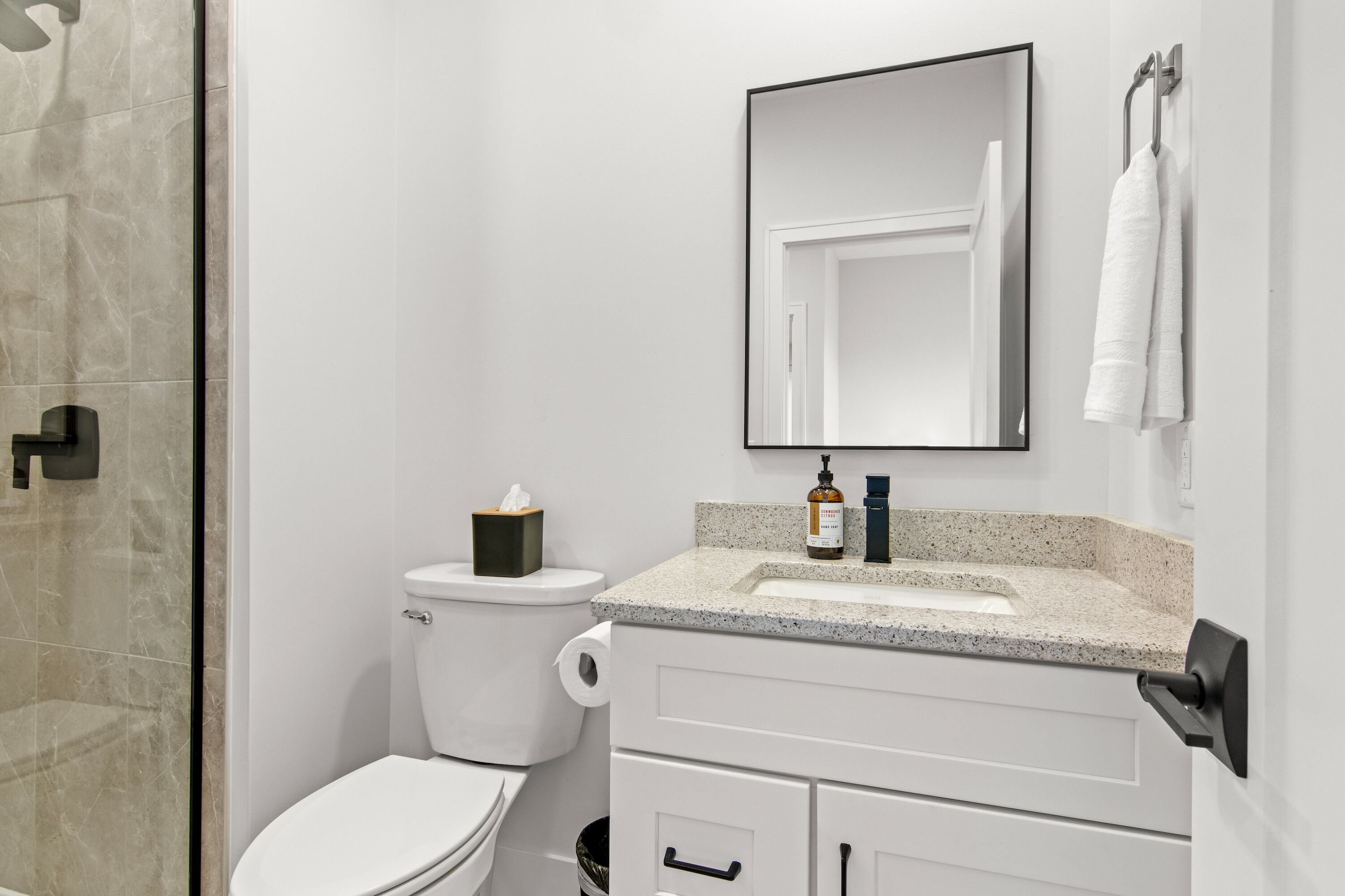 A modern bathroom with a toilet, sink, and mirror.