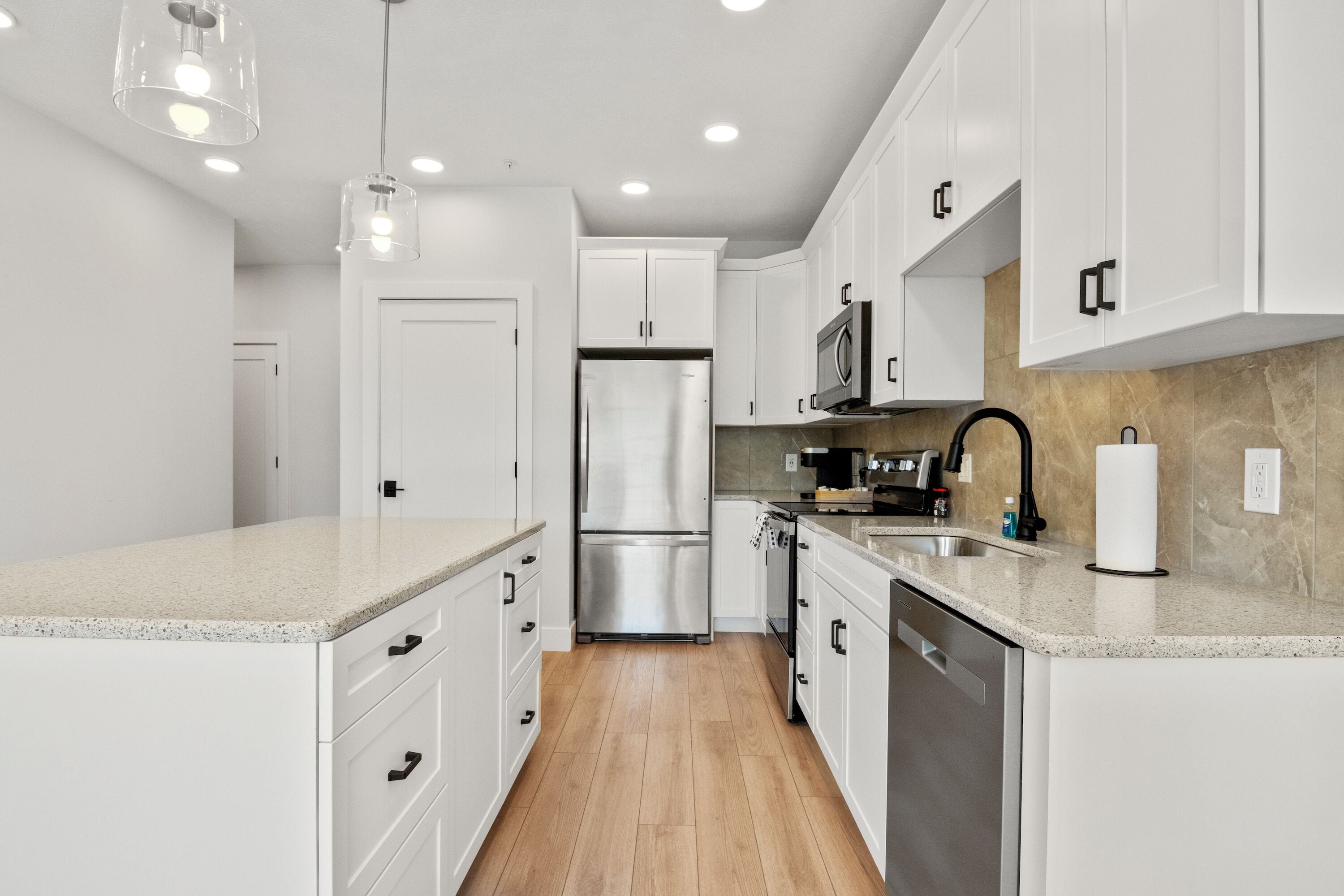 A modern kitchen with white cabinets, stainless steel appliances, and a granite countertop.