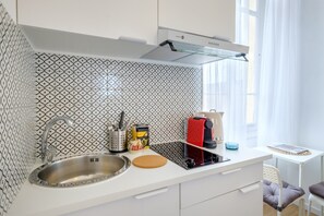 Cocina moderna con salpicadero estampado, pileta de acero inoxidable y un pequeño comedor con mesa y sillas.