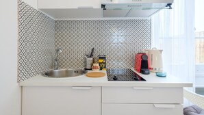Una cocina moderna con un salpicadero estampado, un lavamanos de acero inoxidable, una cafetera y un hervidor.