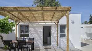 A covered outdoor dining area with a table and chairs, a pergola, and a view of a modern building with large windows. - Country House 'Valle Conil' with Private Pool, Wi-Fi and Air Conditioning (Conil de la Frontera)