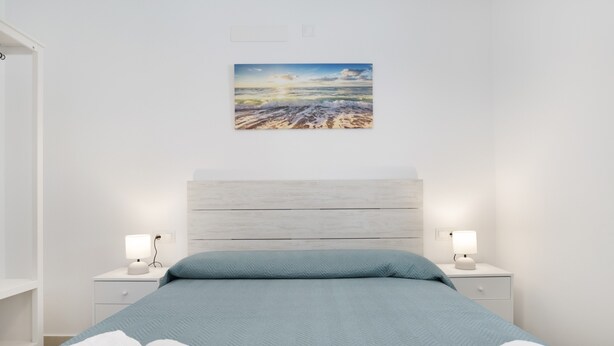 A bedroom with a bed, two bedside tables with lamps, a wall-mounted artwork, and a white wardrobe. - Country House 'Valle Conil' with Private Pool, Wi-Fi and Air Conditioning (Conil de la Frontera)