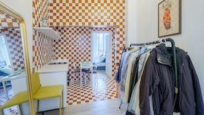 A room with a checkered floor, a desk with a chair, a coat rack, and a bed with a window. - Apartment 'Jolie Proche Monaco' with Wi-Fi (Beausoleil)