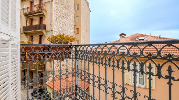 A balcony with wrought iron railings, a stone building with a red-tiled roof, and a clear sky. - Apartment 'Jolie Proche Monaco' with Wi-Fi (Beausoleil)