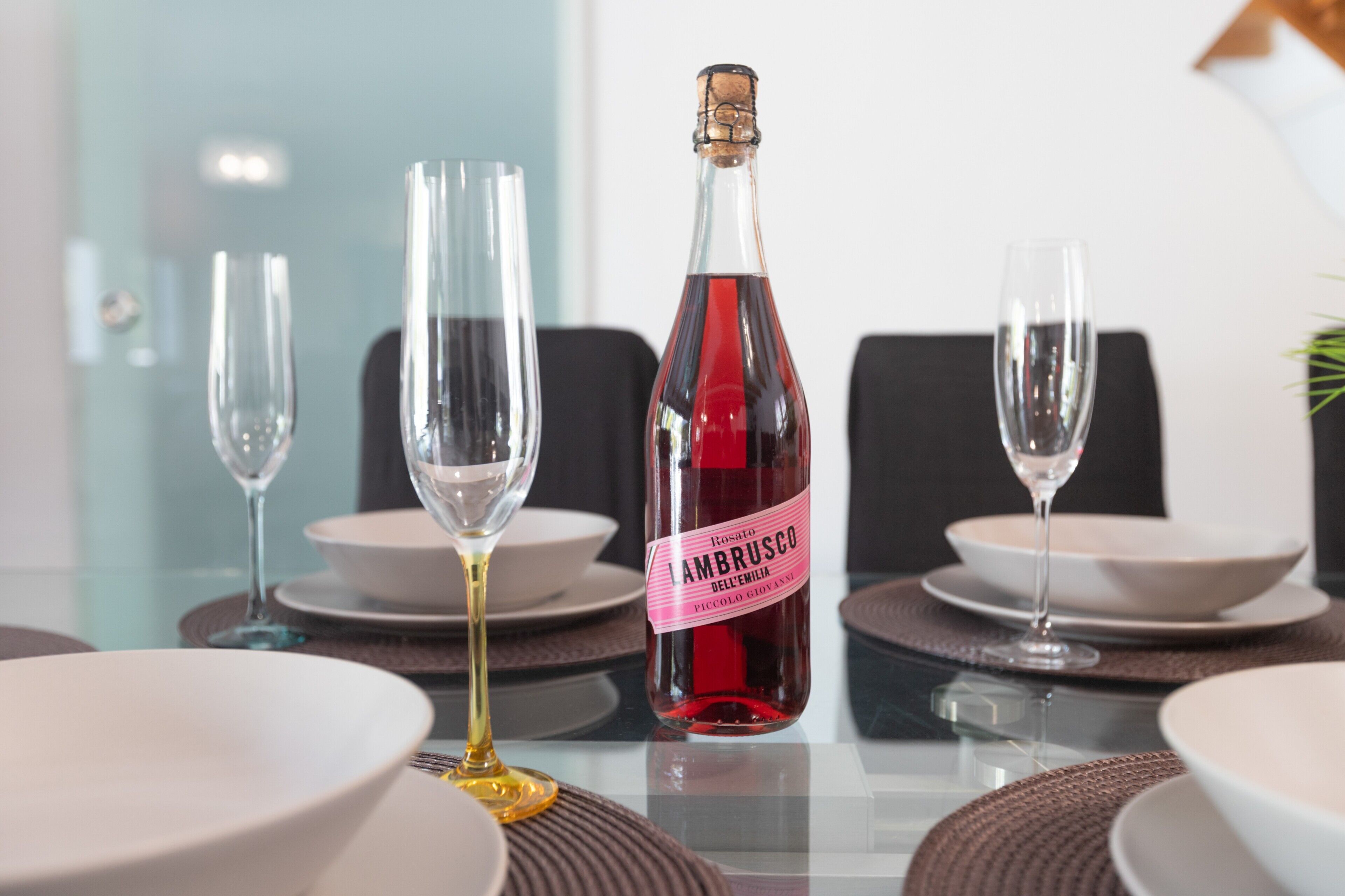 A table set with plates, glasses, and a bottle of wine.