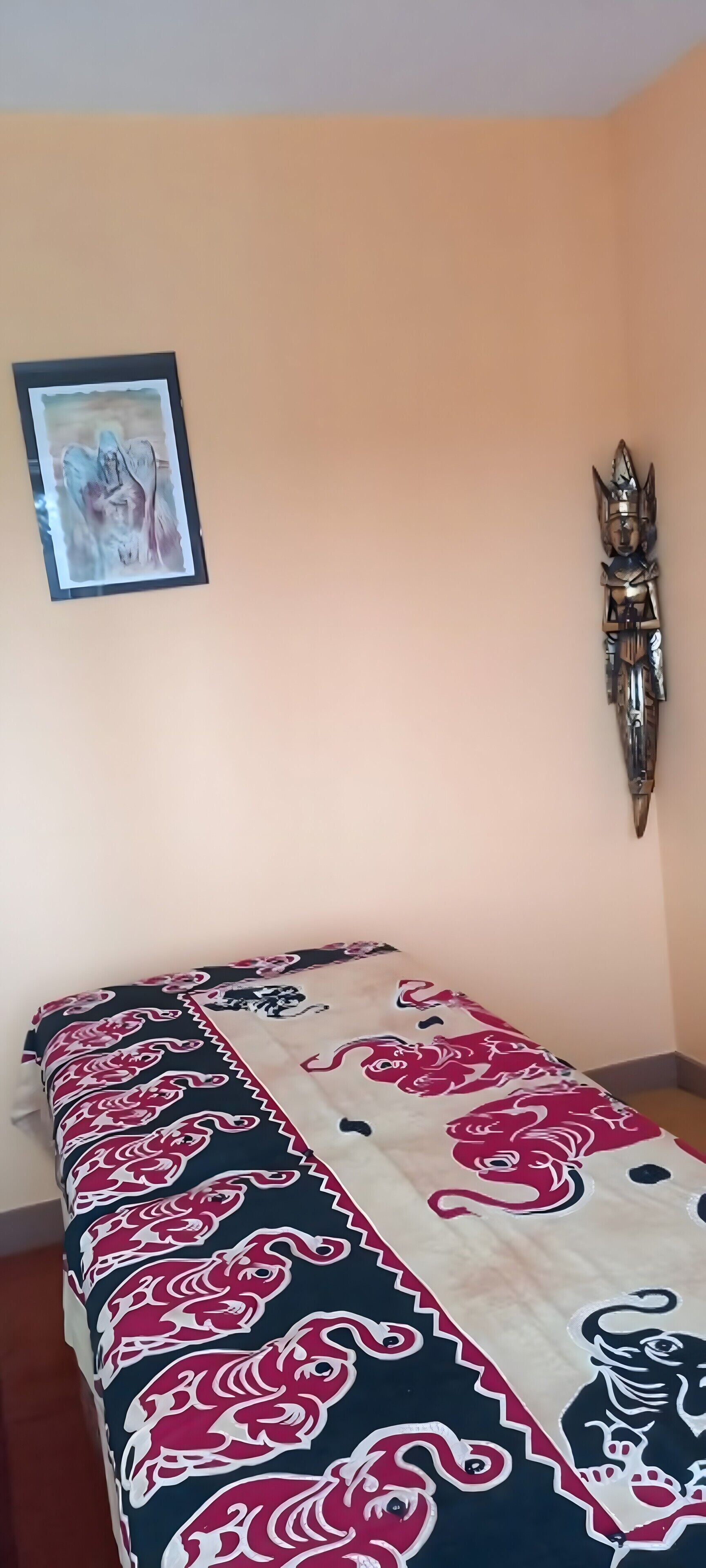 A room with a bed, a framed picture on the wall, and a decorative wall piece.