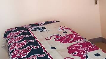 A room with a bed, a framed picture on the wall, and a decorative wall piece.