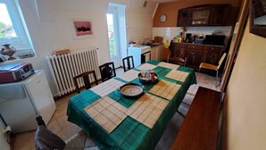 Zona pranzo con tavolo imbandito per quattro, cucina sullo sfondo e termosifone a parete.