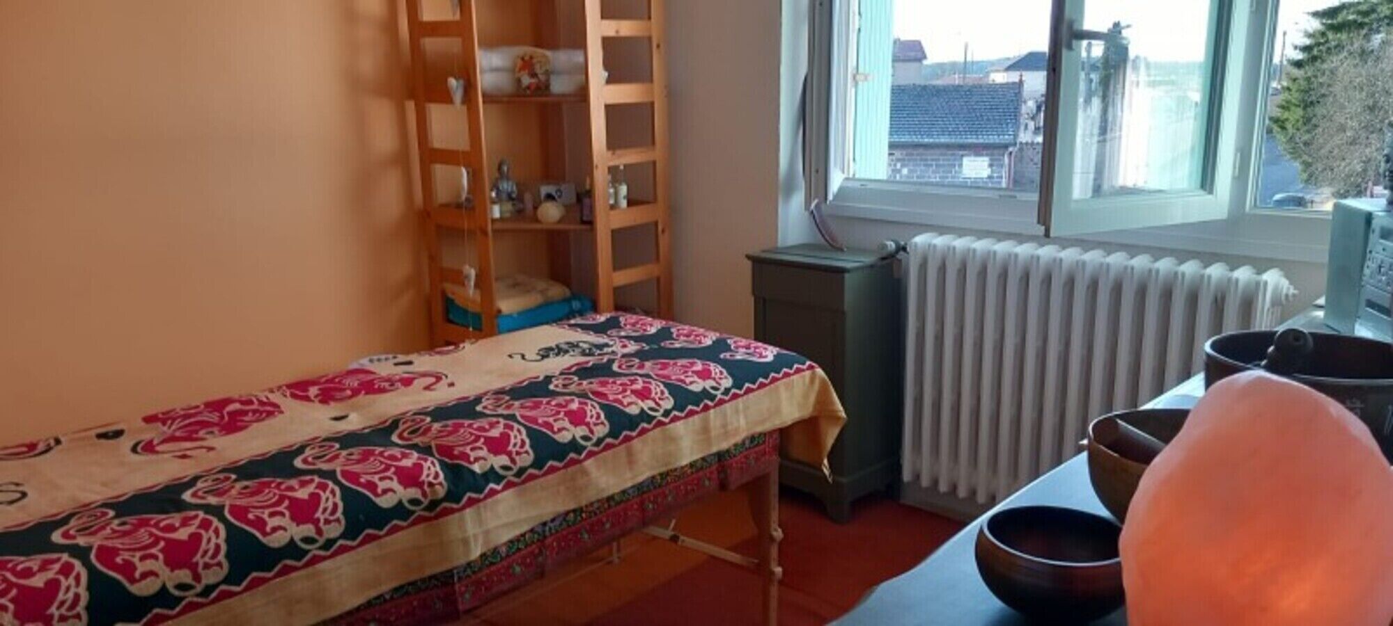 Et værelse med en seng, en radiator, et vindue og en træstige.