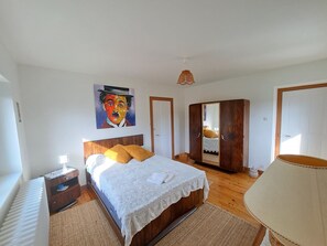 A bedroom with a bed, a wardrobe, a painting, and a lamp.