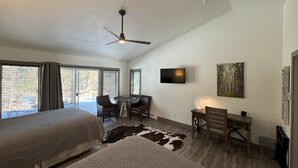 A hotel room with two beds, a ceiling fan, a TV, a desk with chairs, and a cowhide rug. - The Golf Club at Fox Acres (Red Feather Lakes)
