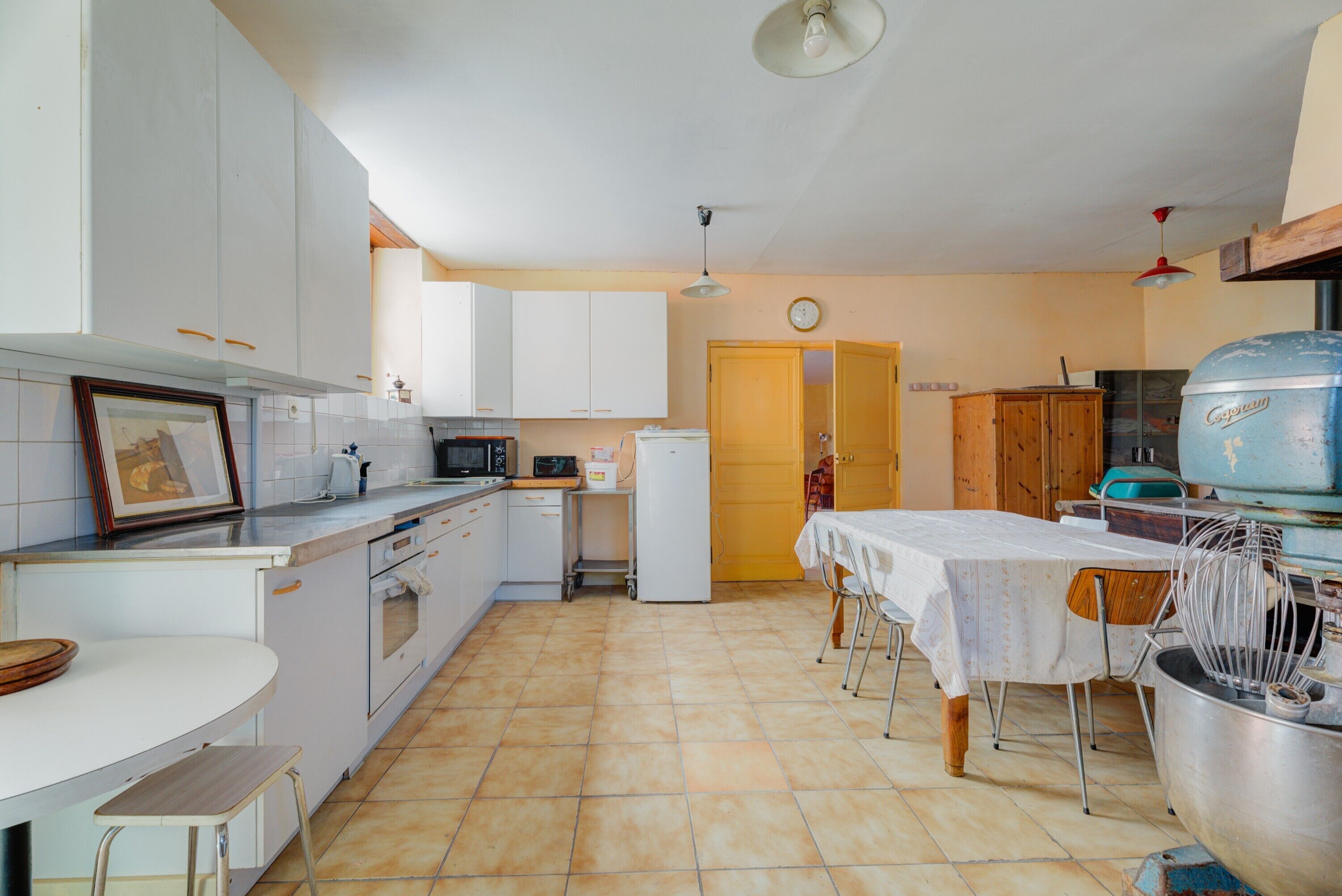 A kitchen with white cabinets, a dining table, and a large pot.