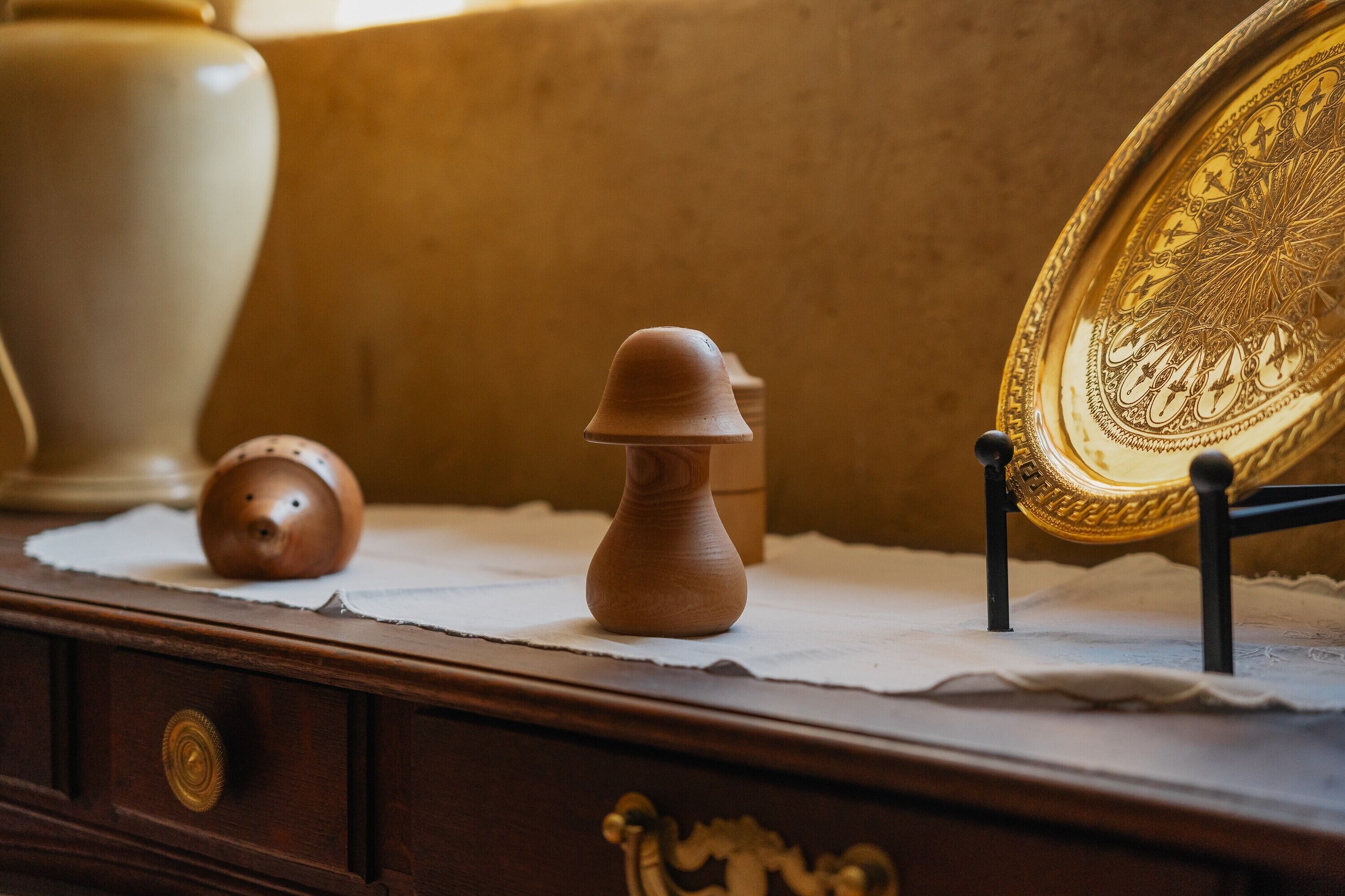 A wooden desk with a decorative plate, a small wooden object, and a ceramic pot.