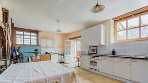Une cuisine avec des meubles blancs, un appareil électroménager bleu et une table à manger avec une chaise.