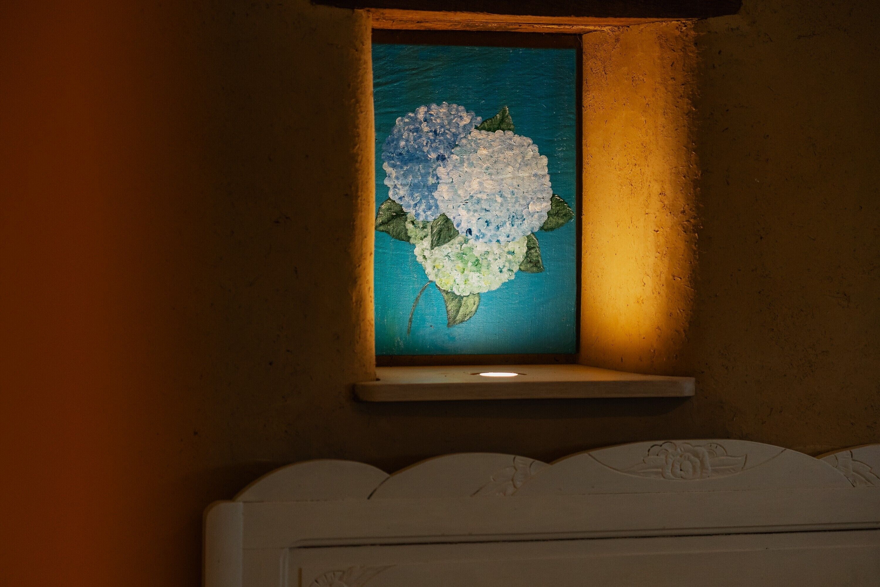 A framed artwork of a blue and white flower on a wall.