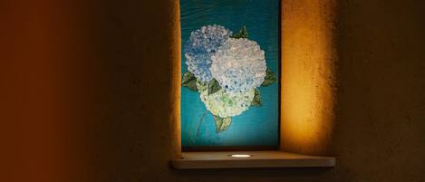 A framed artwork of a blue and white flower on a wall.