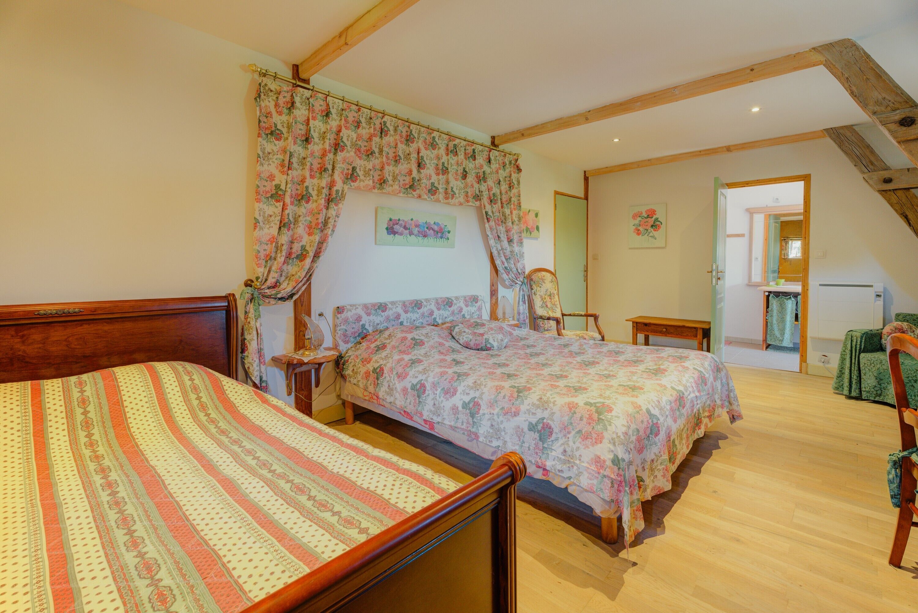 Un dormitorio con una cama de madera, una mesita de noche, una silla y una escalera que conduce a otra habitación.