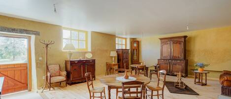 A room with a wooden dining table, chairs, a cabinet, and a lamp.