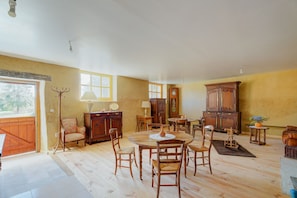 A room with a wooden dining table, chairs, a cabinet, and a lamp. - 'Les Hortensias Roses' Guest Room (Boisgervilly)