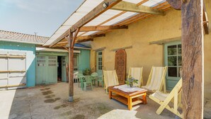 Un espace extérieur abrité, équipé d’une table, de chaises et de chevalets, ce qui laisse supposer qu’il est destiné aux activités de plein air ou à la détente.