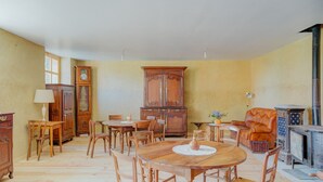 Une salle à manger avec une table en bois, des chaises, un buffet et une cheminée.