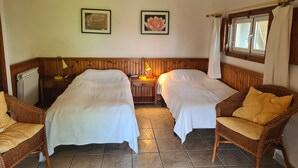 A room with two beds, a nightstand with lamps, wicker chairs, and two framed pictures on the wall. - Rural House 'El Valle' in Sierra de Gredos, Pool and Scenic Views (Piedralaves)