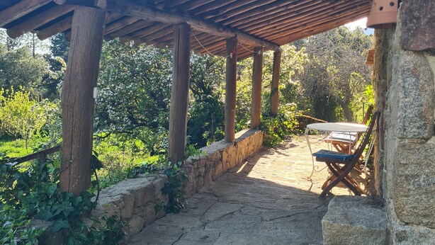A stone patio with a wooden pergola, stone walls, and a table with chairs. - Rural House 'El Valle' in Sierra de Gredos, Pool and Scenic Views (Piedralaves)