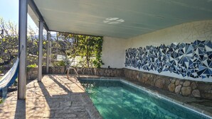 A swimming pool with stone tiles, a metal chair, and a hammock. - Rural House 'El Valle' in Sierra de Gredos, Pool and Scenic Views (Piedralaves)