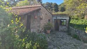 A stone building with a tiled roof, a small garden area with potted plants, and a stone pathway leading to the entrance. - Rural House 'El Valle' in Sierra de Gredos, Pool and Scenic Views (Piedralaves)