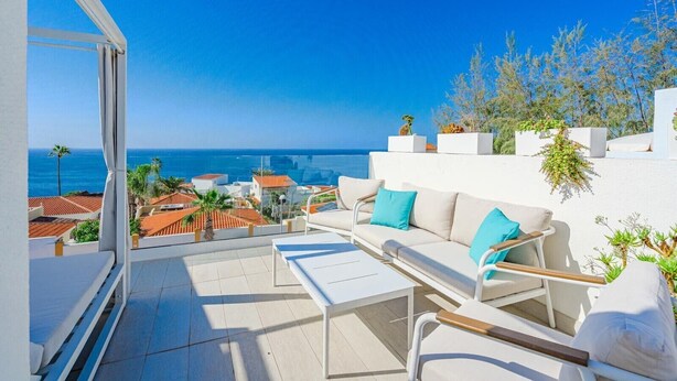 A balcony with a white sofa, a small table, and potted plants. - Vacation Home 'La Perla' with Sea View, Wi-Fi and Air Conditioning (Callao Salvaje)