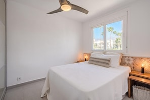 A bedroom with a bed, a window with a view, a ceiling fan, and bedside lamps. - Vacation Home 'La Perla' with Sea View, Wi-Fi and Air Conditioning (Callao Salvaje)