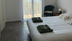 Ein Hotelzimmer mit Bett, Stuhl, Nachttisch und einem Fenster mit Vorhängen.