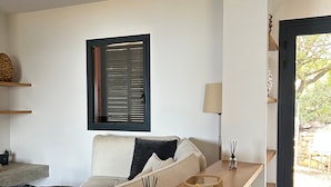 Ein modernes Wohnzimmer mit einer Couch, einem Holztisch, einer Lampe und einem Fenster mit Jalousien.
