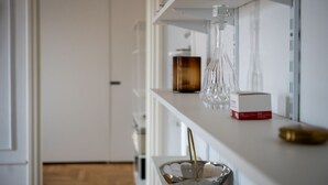 A kitchen with white shelves, a clear glass vase, a metal bowl, and a red box. - La Casa di Gylda - luxe flat (Milano)
