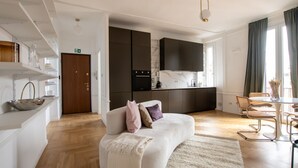 A modern living room with a sofa, a dining area, and a kitchen with a TV. - La Casa di Gylda - luxe flat (Milano)