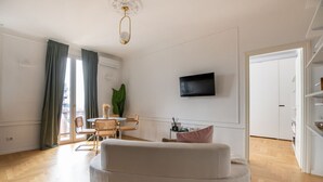 A modern living room with a sofa, a TV mounted on the wall, and a dining area with chairs and a table. - La Casa di Gylda - luxe flat (Milano)