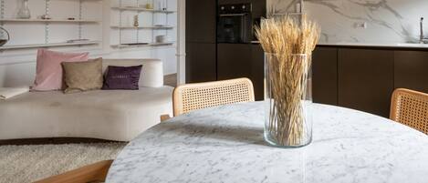 A modern kitchen with dark cabinets, white shelves, and a marble countertop.