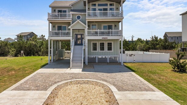 A multi-story building with balconies, a central staircase, and a sign reading "Island Oasis." - 7240- Island Oasis - Dog-Friendly Salvo Home w/ Pool & Hot Tub (Salvo)
