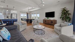 A modern living room with a gray sofa, a round coffee table, and a large plant. - 7240- Island Oasis - Dog-Friendly Salvo Home w/ Pool & Hot Tub (Salvo)