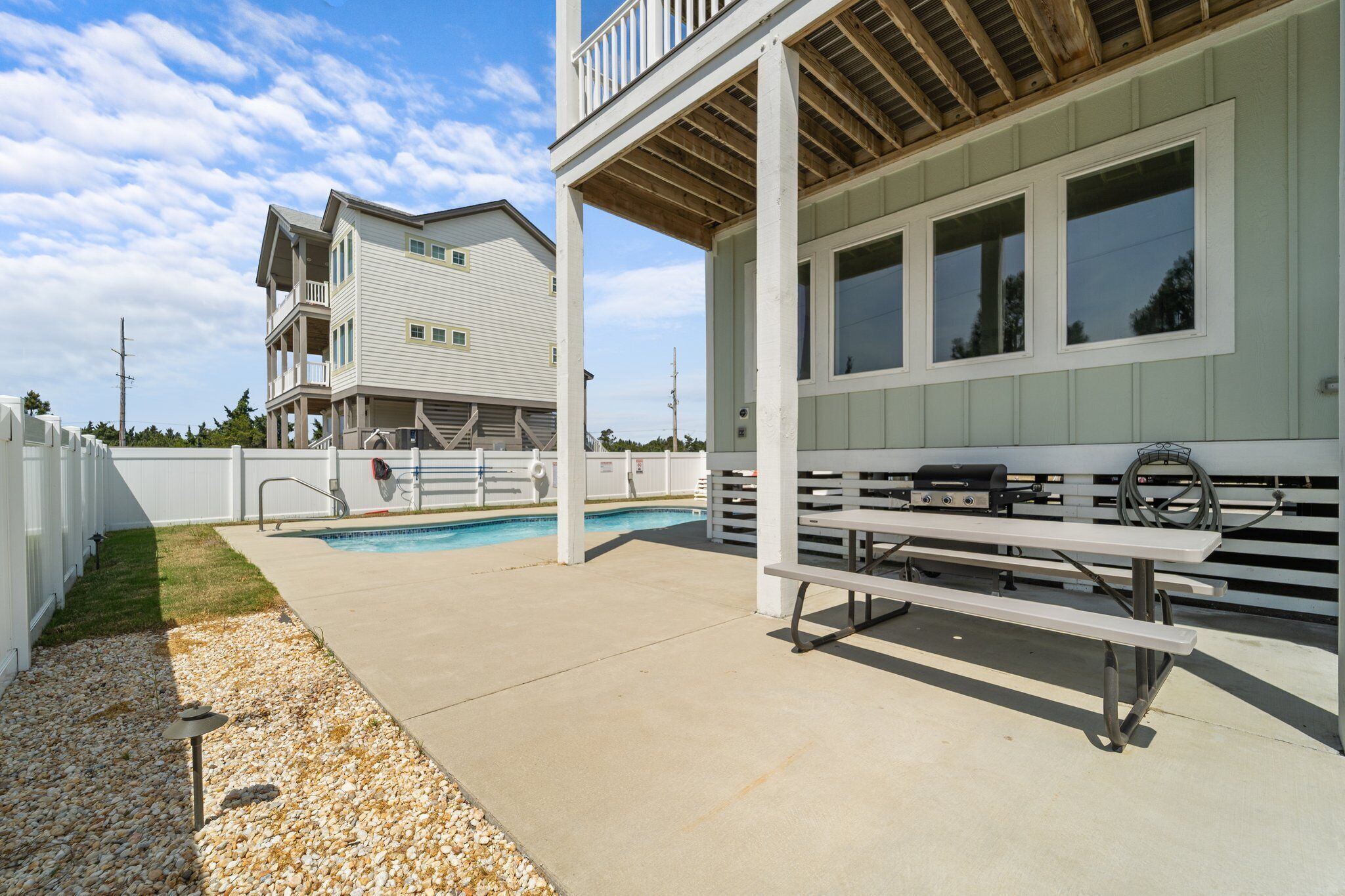 A two-story building with a balcony, a pool, and a picnic table.