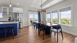 A modern kitchen with a large island, bar stools, and a dining area with a long table and chairs. - 7240- Island Oasis - Dog-Friendly Salvo Home w/ Pool & Hot Tub (Salvo)