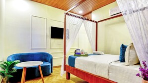 A bedroom with a four-poster bed, a blue sofa, a small round table, and a potted plant. - THE Solitaire Residency  (Kalyan)