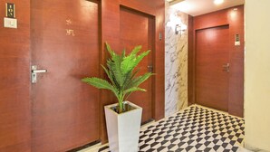 A hallway with wooden doors, a potted plant, and a checkered floor. - THE Solitaire Residency  (Kalyan)