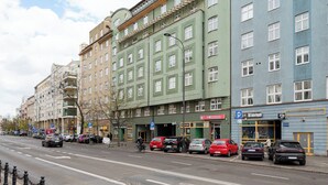 Vista de la calle con edificios de varios pisos, coches aparcados y un ciclista.