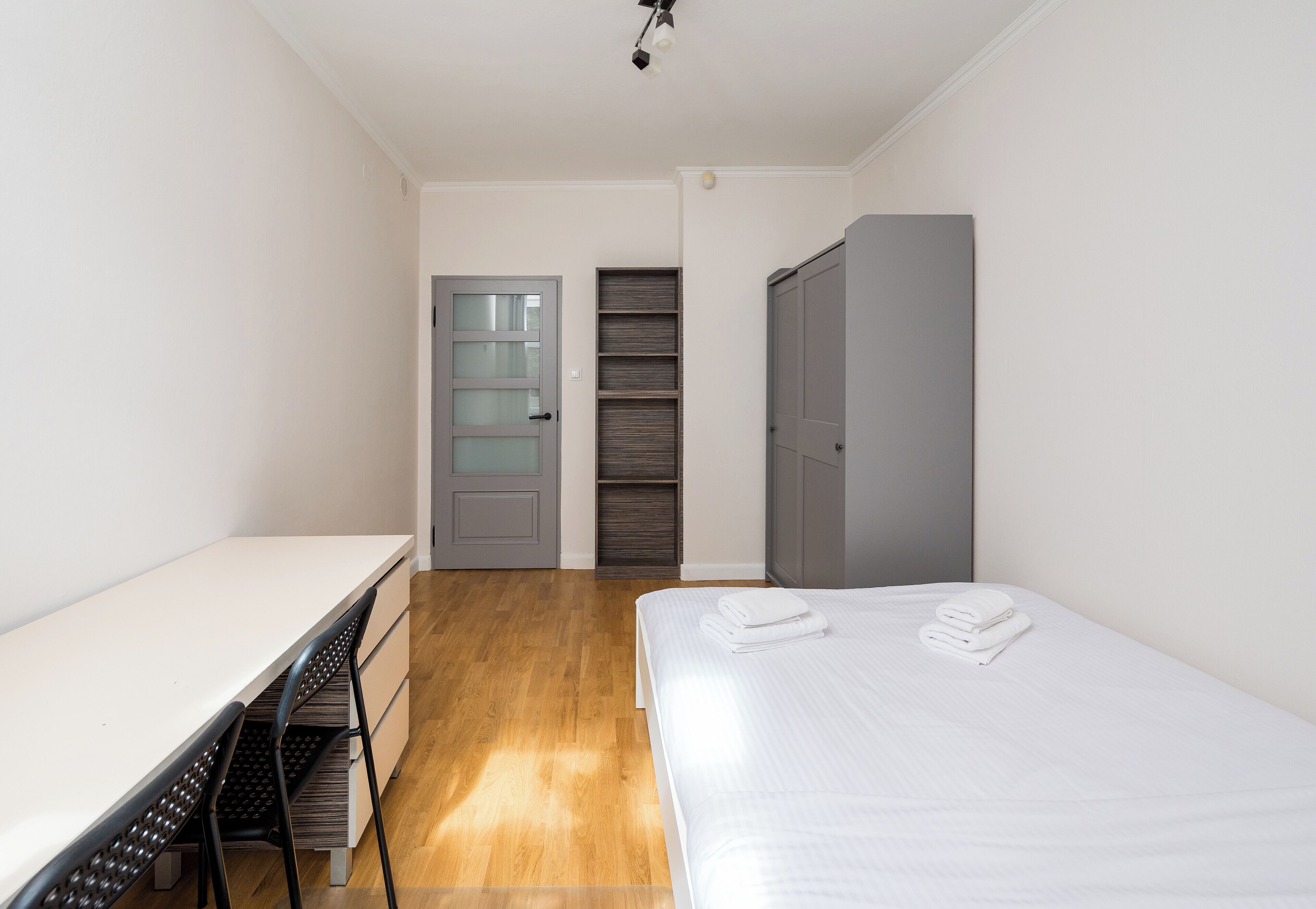 A bedroom with a bed, a desk, and a wardrobe.