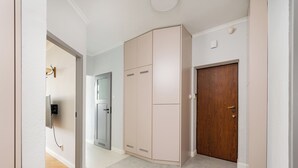 Un pasillo con un armario color beige, una puerta de madera y un interruptor de luz en la pared.