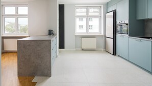 Una cocina moderna con armarios azul claro, una isla central y una ventana con vistas a edificios.
