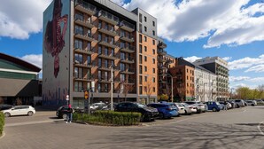 En flervåningsbyggnad med bostäder, balkonger, en parkeringsplats och en väggmålning på sidan.